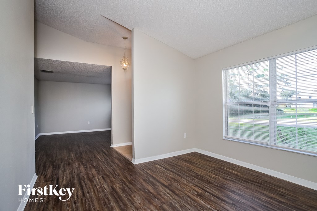 A room with wooden floors and a window with blinds.