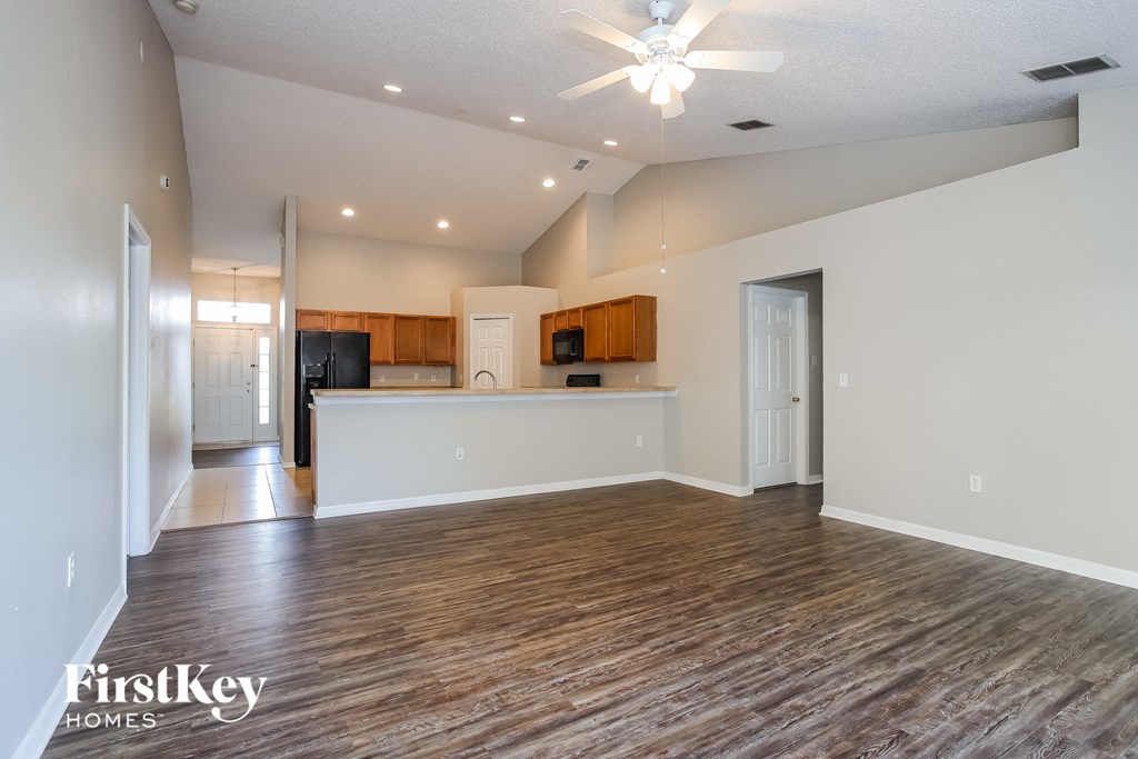 A spacious room with wooden flooring and a ceiling fan.