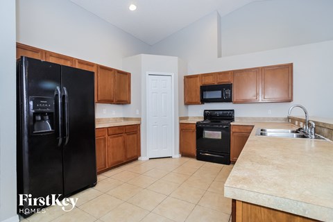 A kitchen with a black fridge, microwave, oven and sink.