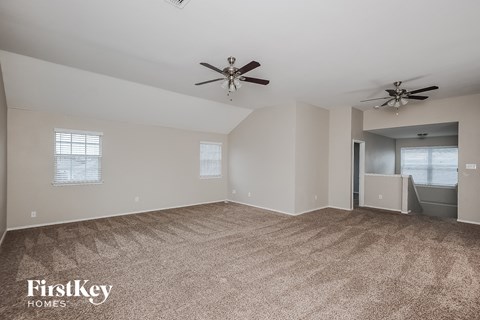 a living room with carpet and two ceiling fans
