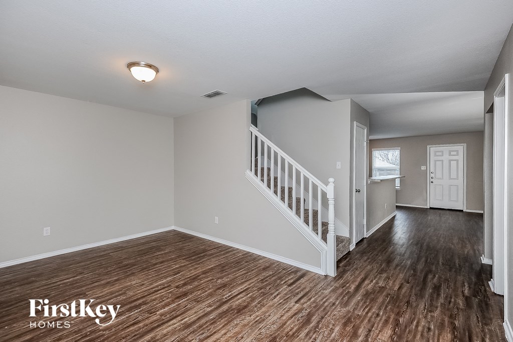 the living room and dining room of a house with wood flooring and a staircase