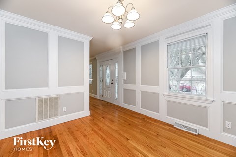 the living room and dining room of a house with white walls and wood floors