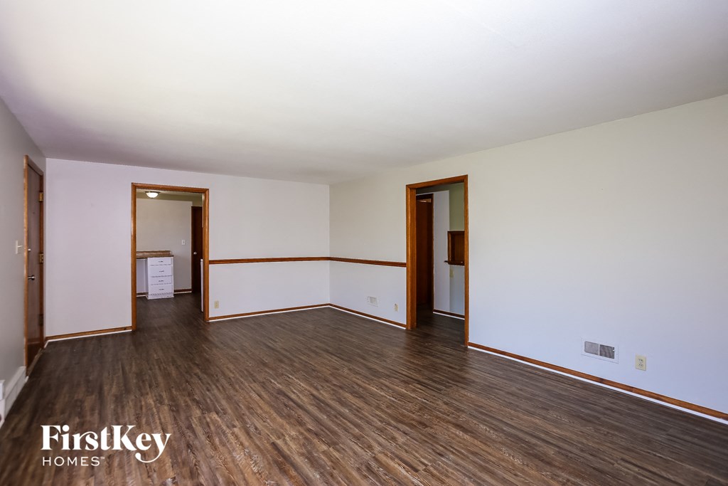 an empty living room with wood floors and white walls