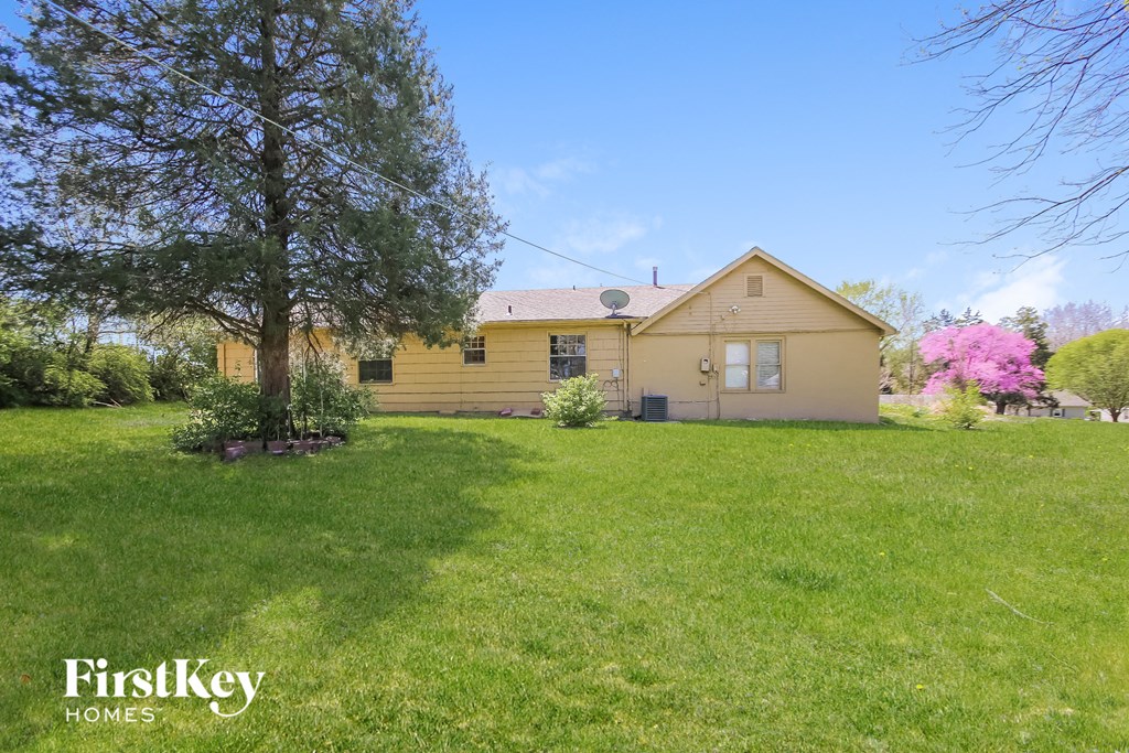 a yellow house with a green lawn and a tree