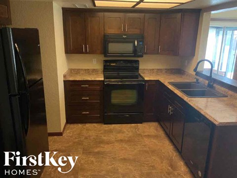 A kitchen with brown cabinets and black appliances.