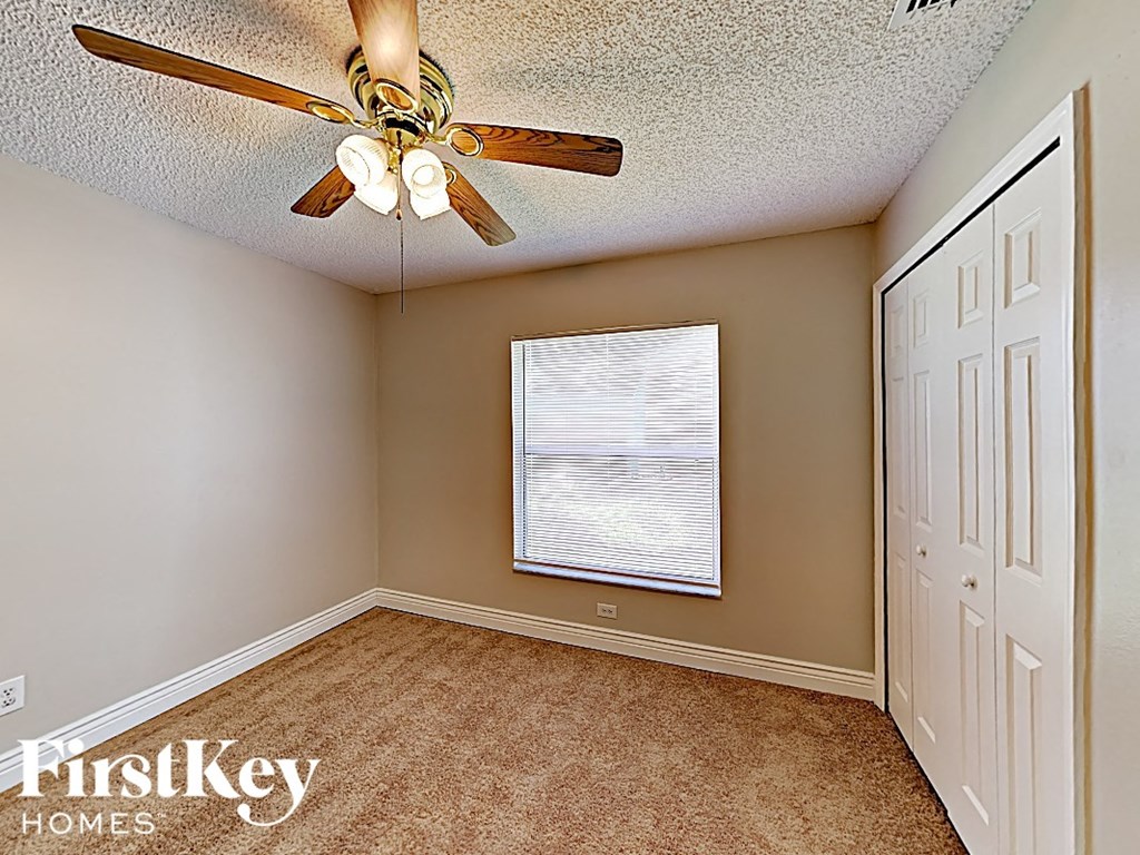 an empty bedroom with a ceiling fan and a window