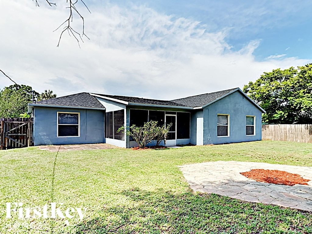 a small blue house with a yard and a patio