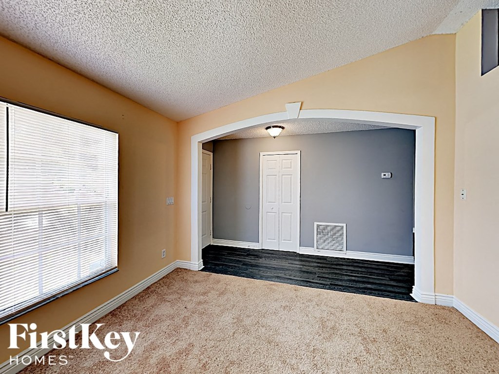 an empty living room with a large window and a white door