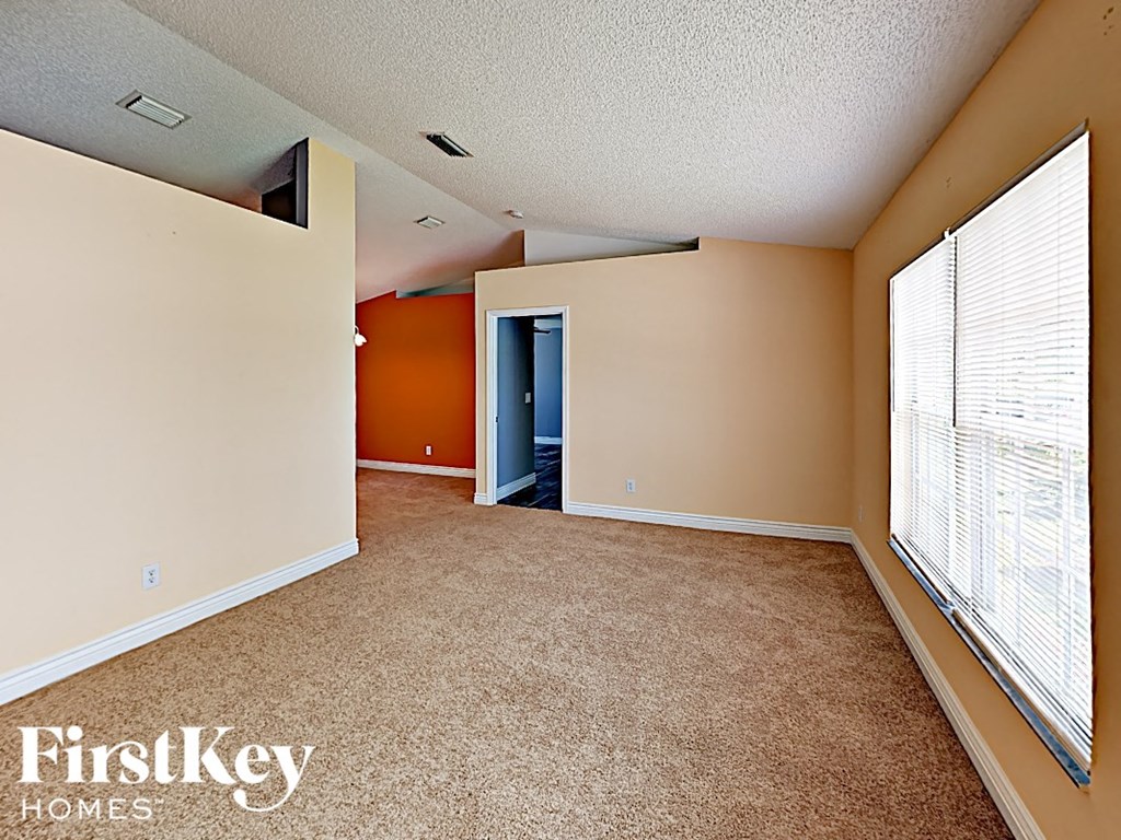 an empty living room with large windows and carpet