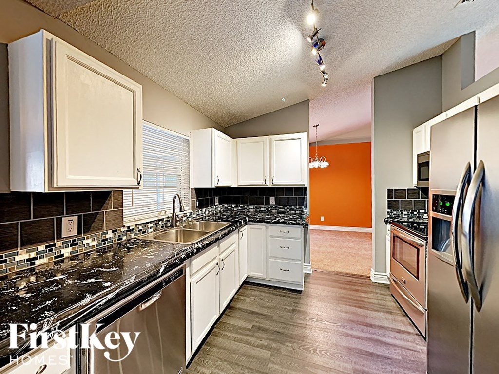 a kitchen with white cabinets and black counter tops