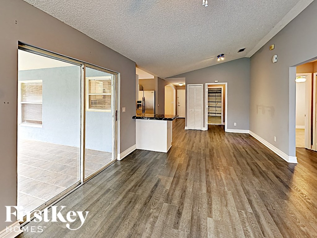 an open living room and kitchen with wood flooring and sliding glass doors