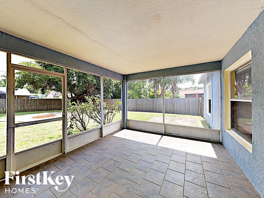 a screened in porch overlooking a backyard with glass doors