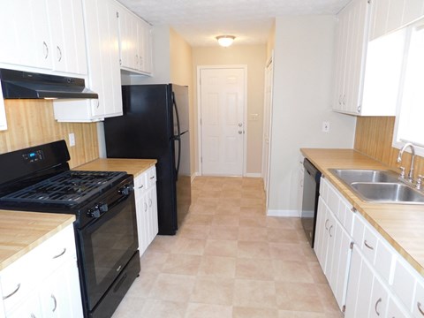 A kitchen with black appliances and white cabinets.