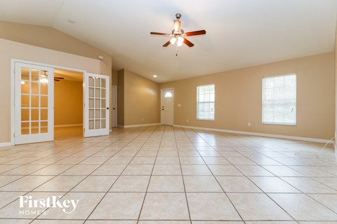 A spacious room with a ceiling fan and tiled flooring.