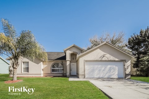A house with a garage and a tree in front of it.