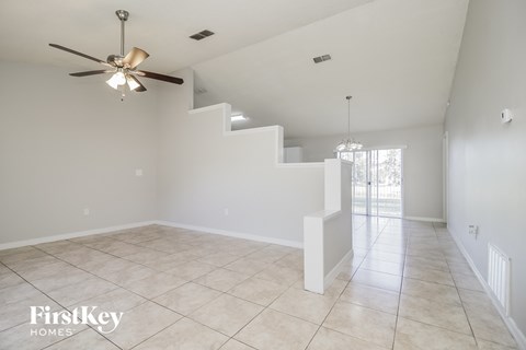 A spacious room with a fan and a staircase.