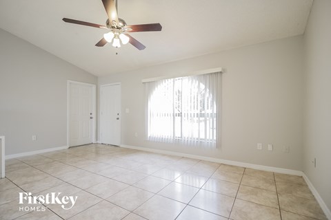 A spacious room with a ceiling fan and tiled flooring.