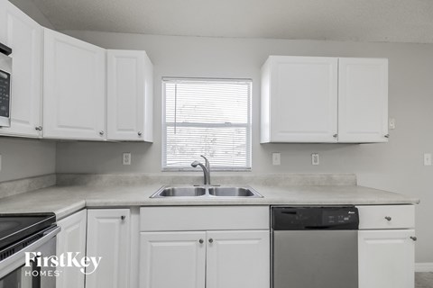 A kitchen with white cabinets and a black stove top oven.