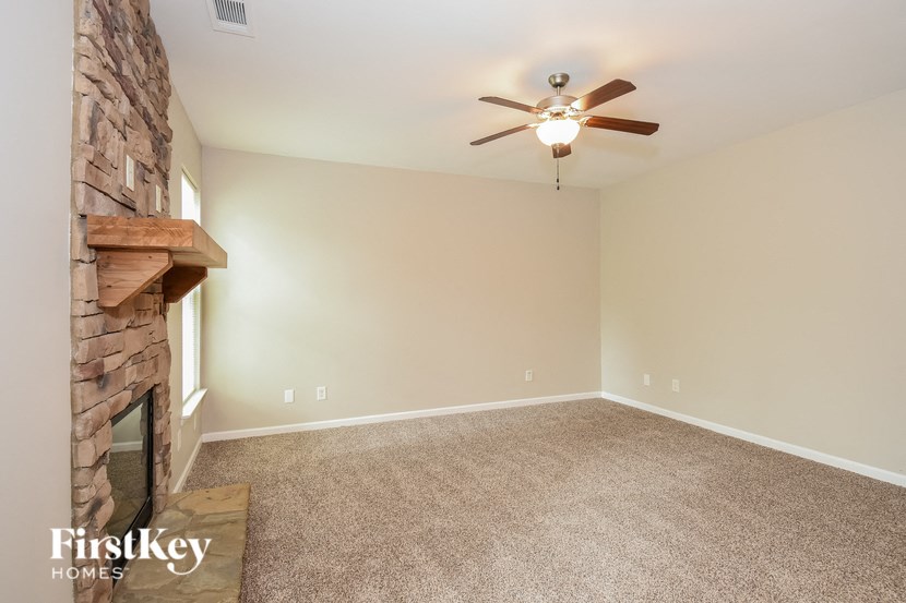 an empty living room with a fireplace and a ceiling fan
