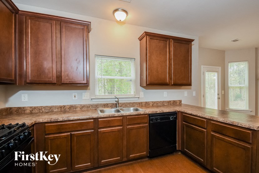 full view of kitchen with maple cabinets and granite counter tops and black appliances