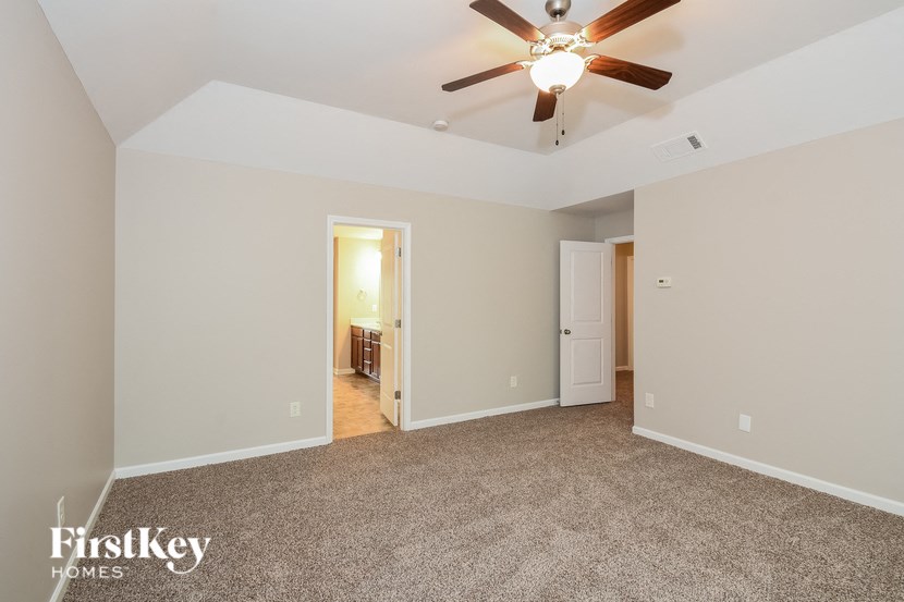 a spacious living room with carpet and a ceiling fan