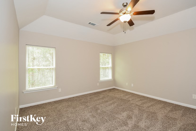 the living room of a home with carpet and a ceiling fan
