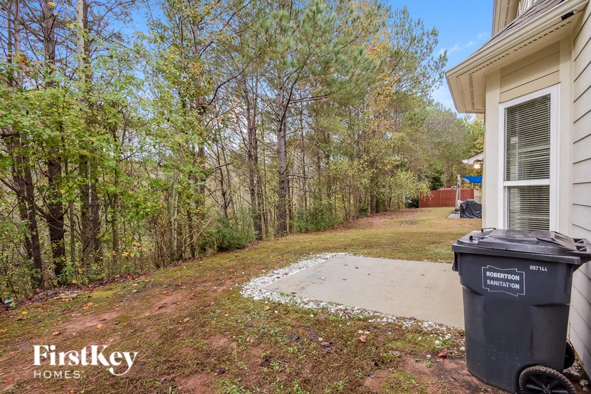 the driveway to the side of the house with a trash can