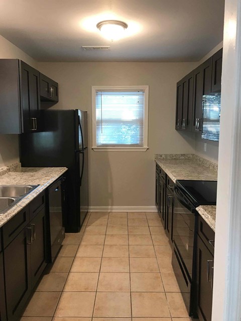 A kitchen with black cabinets and a black fridge.