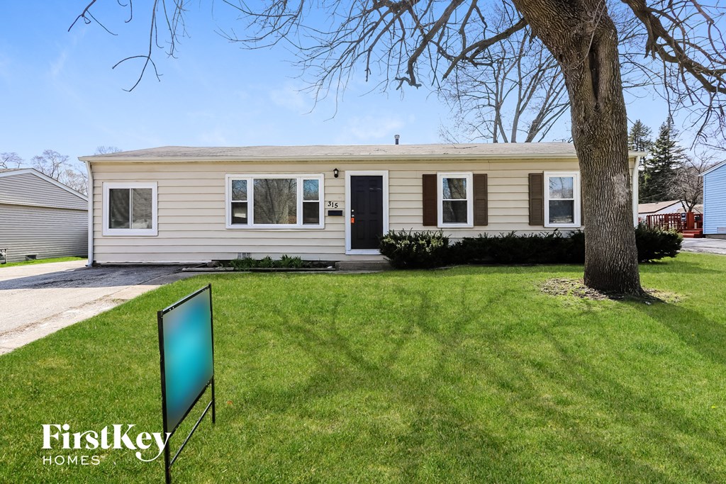 A house with a green lawn and a tree in front of it.