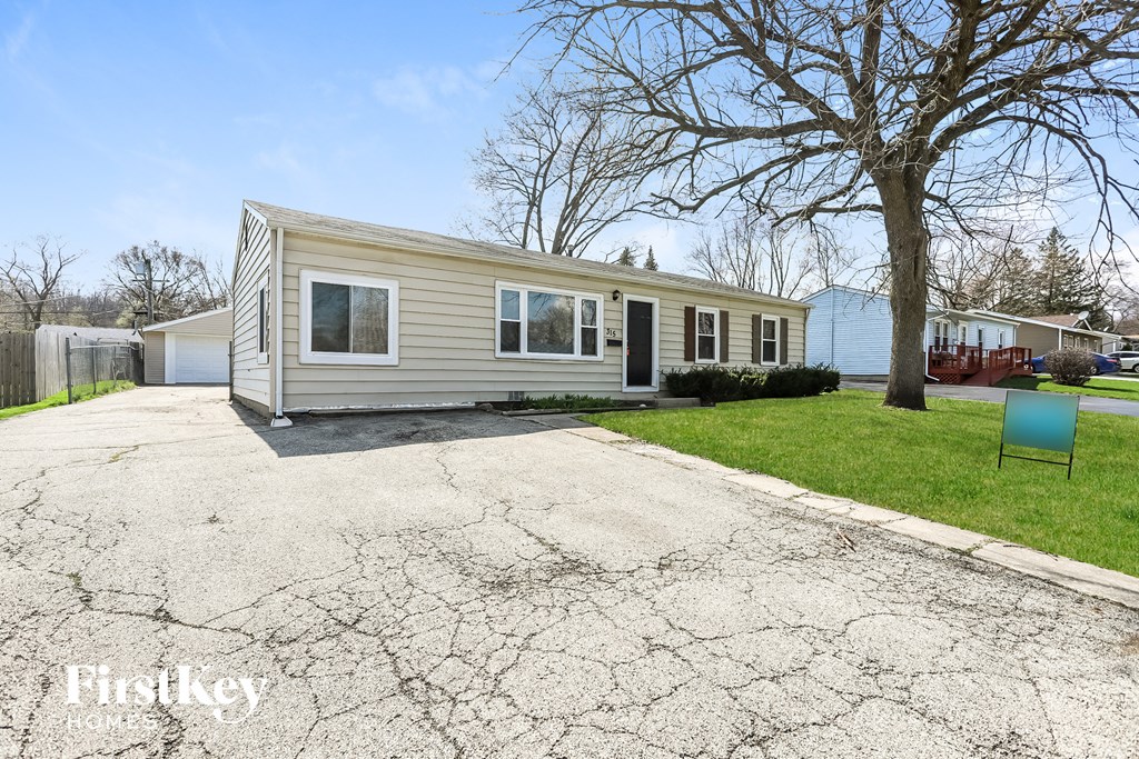 A mobile home is parked in a driveway with a tree in the background.