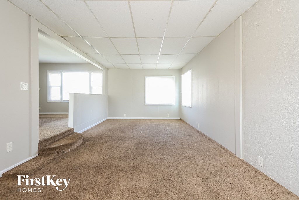 A spacious empty room with carpeted floor and white walls.