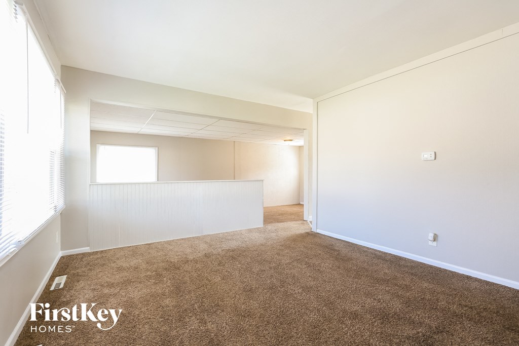A carpeted room with a window and a door.
