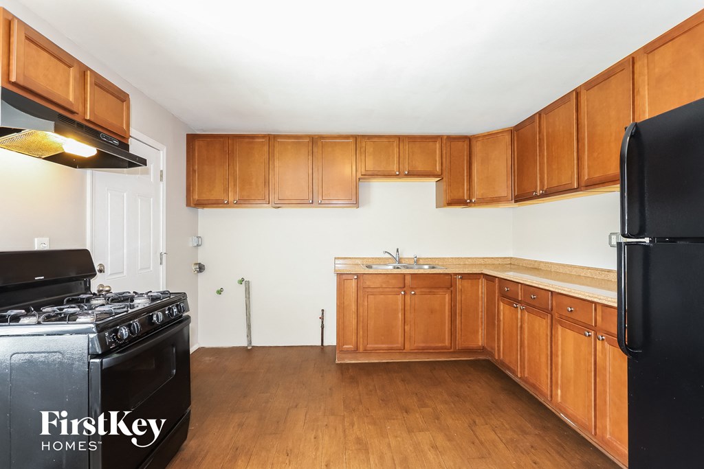 A kitchen with wooden cabinets and a black refrigerator.