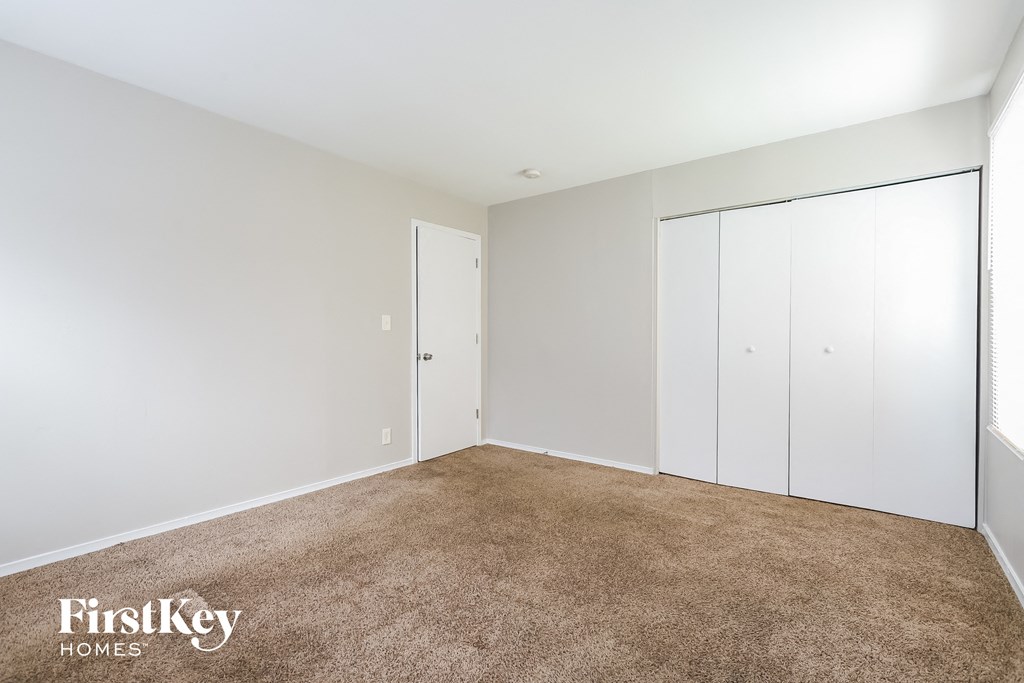 A carpeted room with a white door and a white wall.