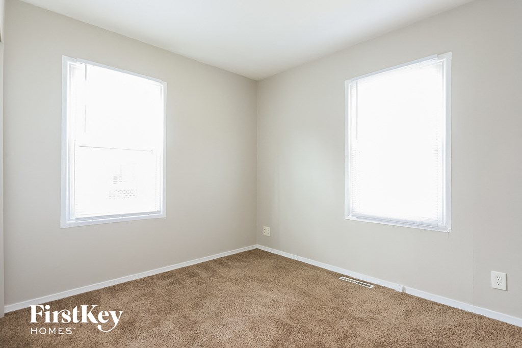 A room with two windows and a carpeted floor.