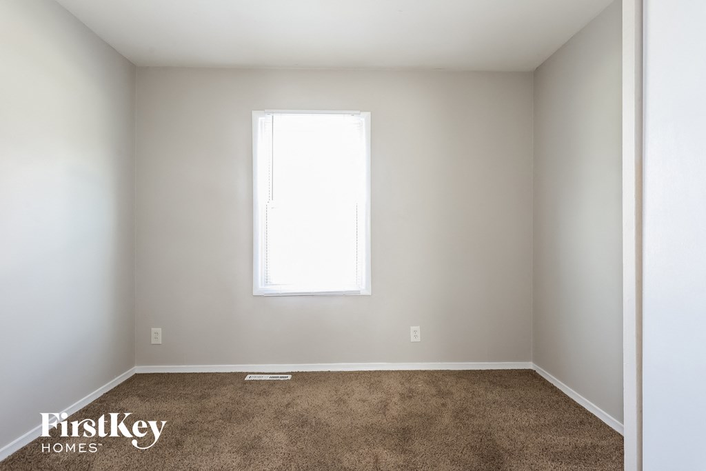 A room with a carpeted floor and a window letting in light.