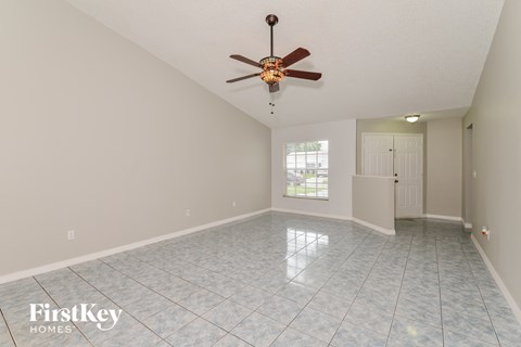 A spacious room with a ceiling fan and tile flooring.