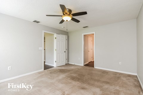 A spacious room with a ceiling fan and carpeted floor.
