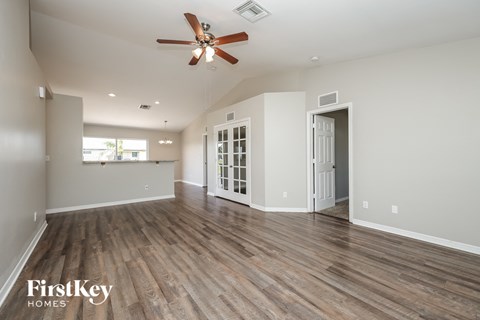 A spacious room with a ceiling fan and wooden flooring.