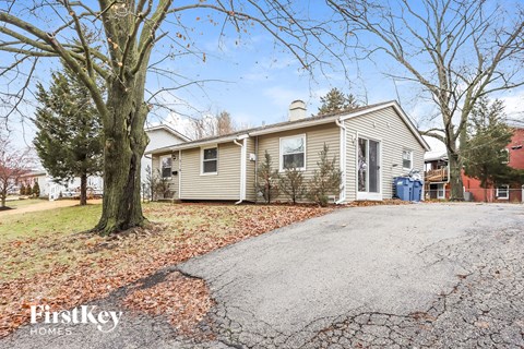 A house with a driveway and trees in the background.