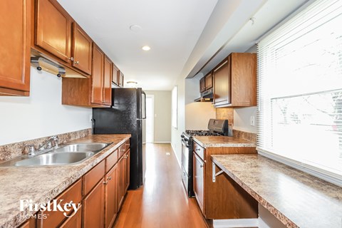 A kitchen with wooden cabinets and a black refrigerator.