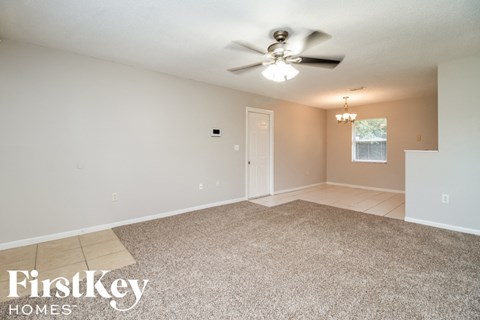 A spacious room with a ceiling fan and carpeted floor.
