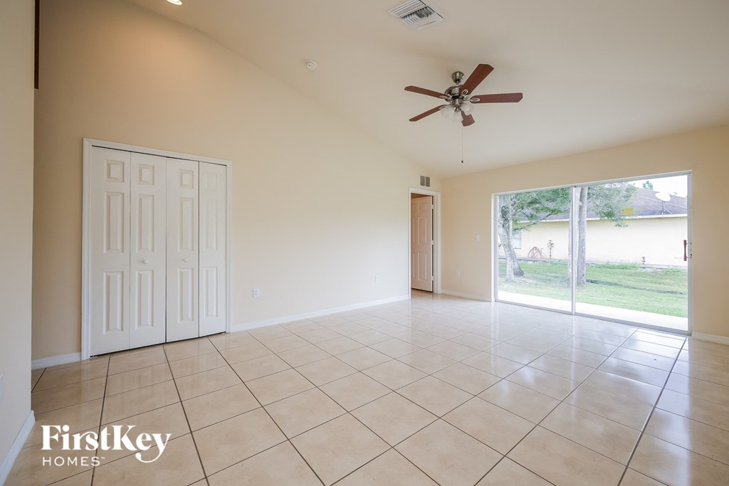 A spacious room with a fan and sliding glass doors.