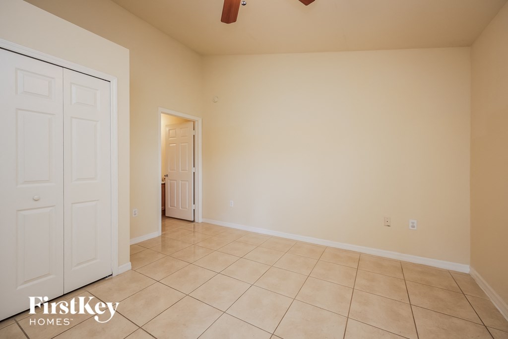 A room with a white door and a fan on the ceiling.