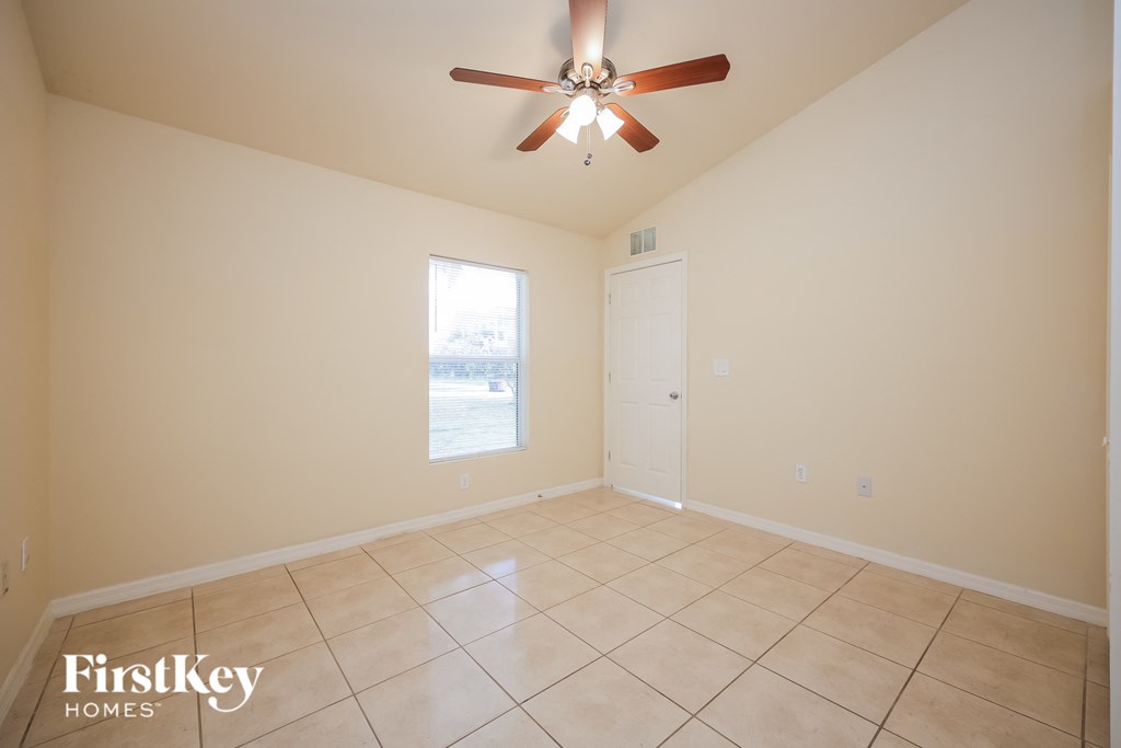 A spacious room with a ceiling fan and tiled floor.