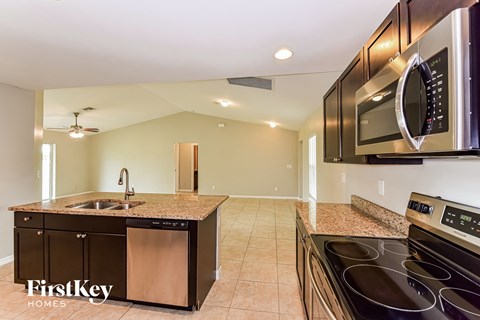 A kitchen with a black stove top oven and a black microwave above it.