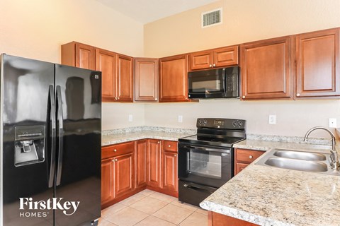 A kitchen with wooden cabinets and a black refrigerator.