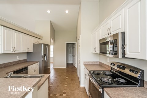 A kitchen with white cabinets and a black stove top oven.