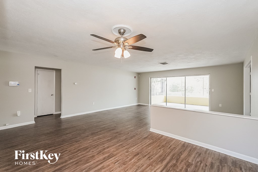 A spacious room with a ceiling fan and wooden flooring.