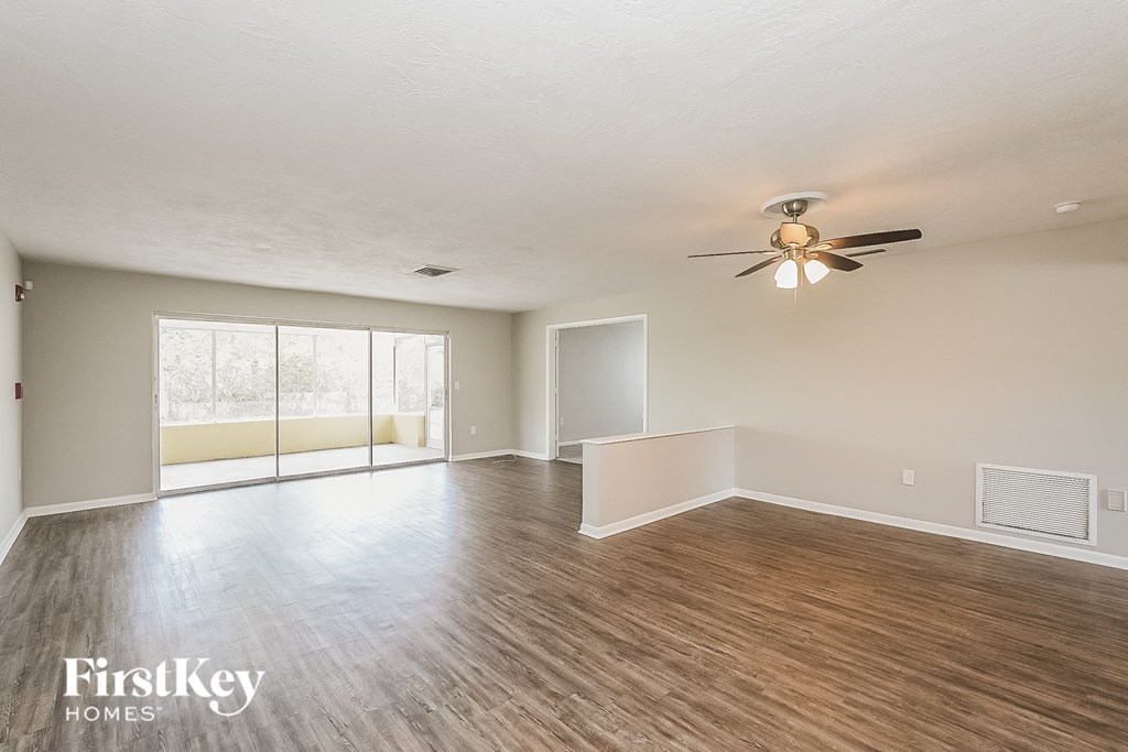 A spacious room with wooden flooring and a ceiling fan.
